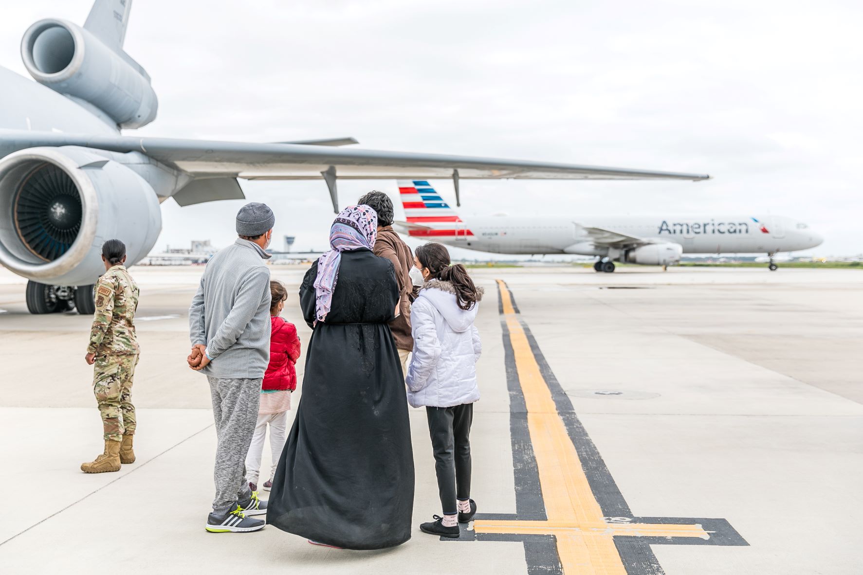 Afghan family standing on airfield looks at PHL airport