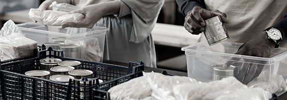 two people putting cans in a container 