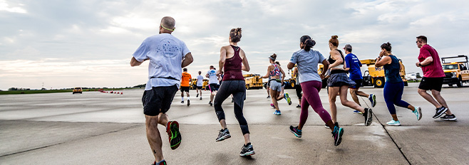 5K Runners on runway with snow equipment in background