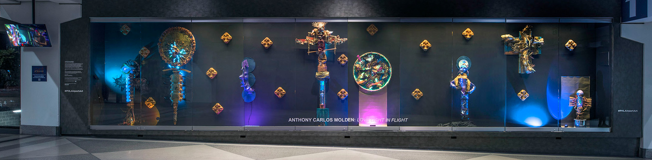 exhibition with blue, pink and purple lights with figures made from recycled material
