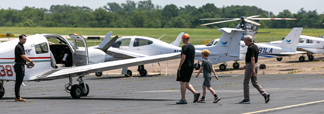 Adults and kids walking in front of private planes at PNE airport