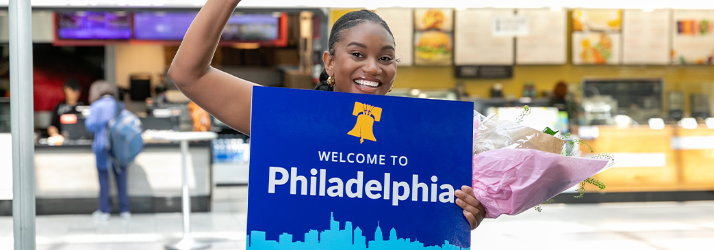 woman holding welcome to Philadelphia sign and flowers 