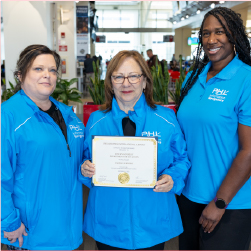 Evelyn standing with coworkers while holding certificate