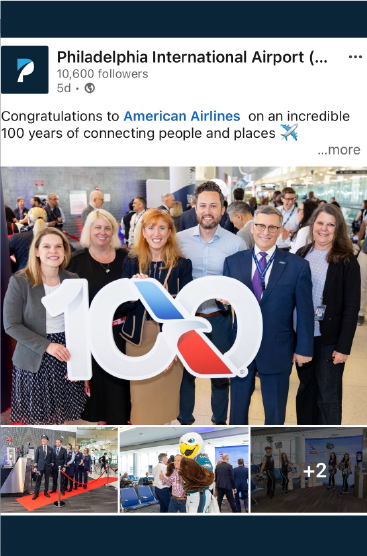 Group of men and women smiling and holding a sign shaped in 100 with the America Airlines logo