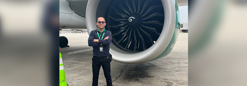 Miguel standing in front of Frontier plane
