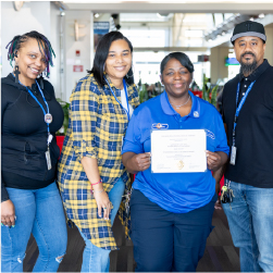 Monique holding certificate with co-workers