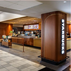 Brown wooden pillar with Starbucks written on it in white letters. Walk-up counter to order food to the left